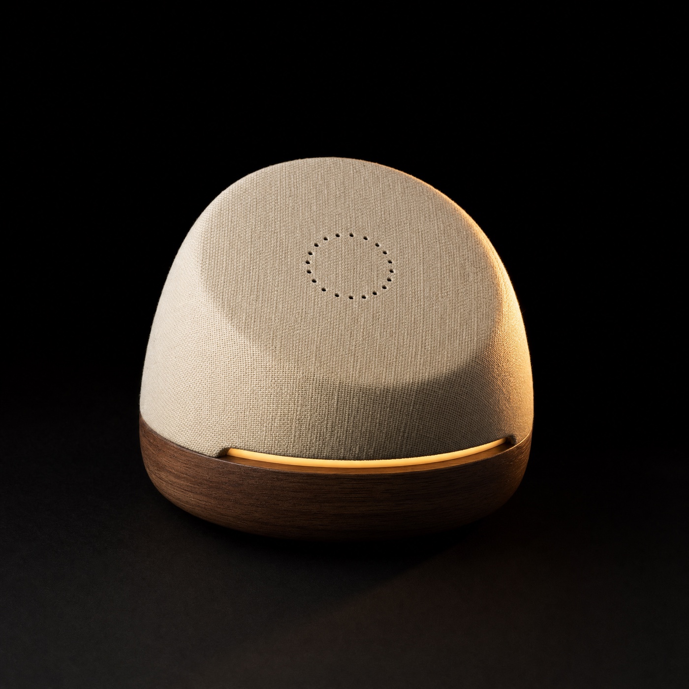 Hank concept: a soft tilted fabric dome on a walnut base, its face turned toward the viewer, with a circle of microphone ports and a warm light under the lip